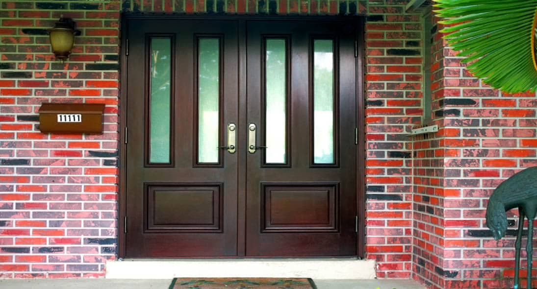 Dark mahogany double entry doors on a brick residence